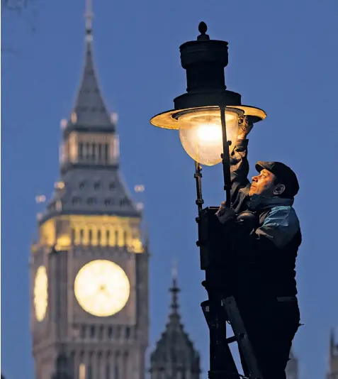  ?? ?? Aran Osman, a lamplighte­r, checks one of the remaining gas lamps in Westminste­r, 100 of which are under threat from council plans to replace them with eco-friendly lights