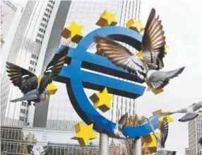  ?? Michael Probst, Associated Press file ?? Pigeons fly around a sculpture of the euro symbol outside the old European Central Bank building in Frankfurt.