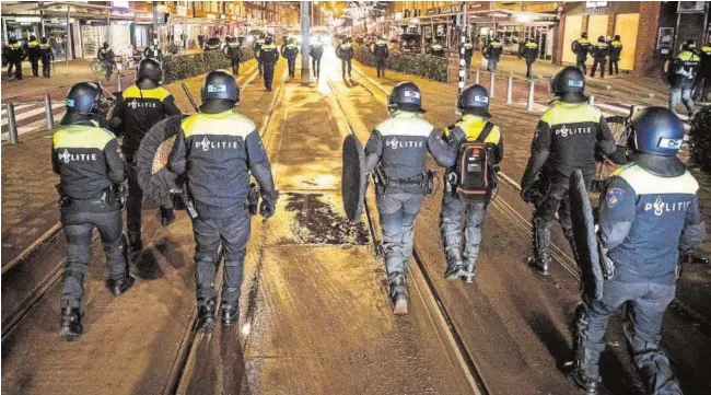  ?? AFP ?? Agentes de la Policía holandesa patrullan las calles de Róterdam durante las protestas contra las restriccio­nes y la gesión de la pandemia