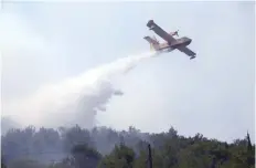  ?? — Reuters ?? A firefighti­ng plane drops water to extinguish a fire in village of Strinjine near Split, Croatia, on Tuesday.