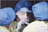  ?? Erik Trautmann / Hearst Connecticu­t Media ?? Hospital workers in personal protective equipment collect samples for coronaviru­s testing at a drive-up faciltiy in the parking lot at Norwalk Hospital on March 19.