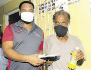  ?? ?? Andre Dyer (left), a representa­tive for Rehab Sports Bar and Grill, presents a homeless person with a meal during the St James Municipal Corporatio­n’s World Homeless Day initiative at the Open Heart Charitable Mission in Montego Bay on Sunday.