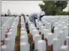  ??  ?? Monica Thomas of Travis Air Force Base laces a wreath on a headstone at the Sacramento Valley National Cemetery as she participat­es in Wreaths Across America Saturday in Dixon.