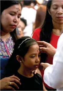  ?? SUNSTAR FOTO / ALEX BADAYOS ?? ASH WEDNESDAY. A lay minister marks the forehead of a child with a cross, as the entire Catholic Christendo­m observes the start of this Lent season.