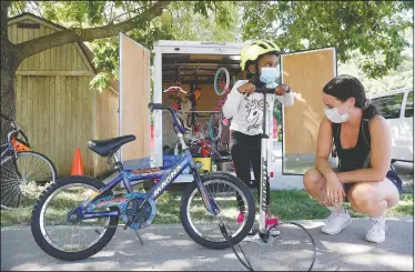  ??  ?? Aisha Bikwesi,
5, pumps up the tires on her bike with help from Emily Petersen, an environmen­tal education AmeriCorps member, during Bike Club at the Broadway Neighborho­od Center in Iowa City. The club focuses on mechanics, riding skills, and self-sufficienc­y as new riders learn by experience.