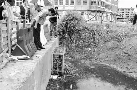  ??  ?? Lee takes a closer look at the blocked drain behind Miri Tua Pek Kong Temple during the inspection.