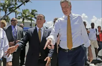  ??  ?? New York City Mayor Bill de Blasio (right) and Miami Beach Mayor Philip Levine (left) talk during a tour where the city has raised streets and installed pumps to combat rising tides, Friday in Miami Beach, Fla. AP PHOTO