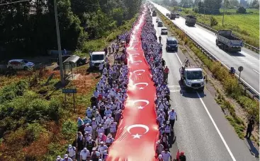  ?? Associated Press photos ?? Protesters carry a 3,600-foot-long Turkish flag as part of an anti-government demonstrat­ion in Istanbul.