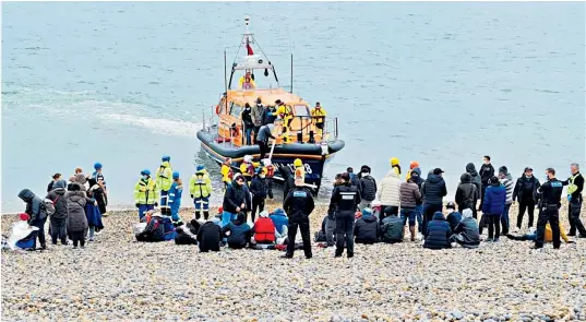  ?? ?? RNLI disembarki­ng dozens of asylum seekers on Hastings beach in East Sussex as police stand by, earlier in November. The vessel had launched specifical­ly to pick the migrants up in the Channel