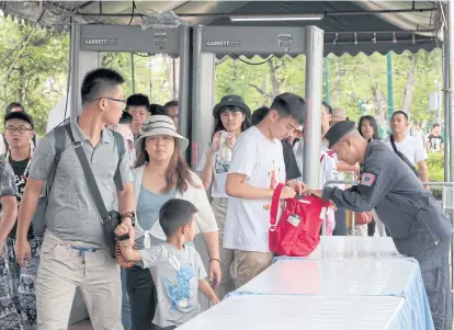  ??  ?? LEFT Tourists at the Grand Palace face tight security yesterday as officers keep an eye out for any irregulari­ties following bombing incidents in Bangkok last Friday. CHANAT KATANYU Just a few bag checks