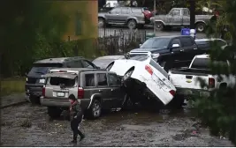  ?? DENIS POROY — THE ASSOCIATED PRESS ?? A woman walks by cars damaged from floods during a rainstorm Monday in San Diego. The city received a record 2.73inches of rain.