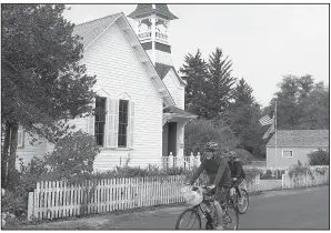  ??  ?? Cyclists pass the old Oystervill­e Church, a gift to the community from founding father R.H. Espy, who donated the land and money for constructi­on in 1892.