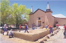  ?? ADOLPHE PIERRE-LOUIS/JOURNAL ?? Volunteers apply mud to the wall outside the Old San Ysidro Church in Corrales in 2017. For the second year in a row, the village was named the safest place in N.M.