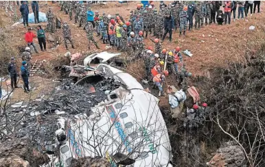  ?? ?? LUGAR. Los rescatista­s sacan el cuerpo de una víctima que murió en el accidente aéreo en Nepal.