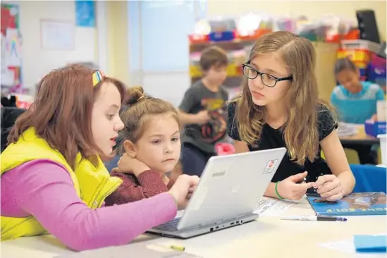  ?? LLOYD FOX/BALTIMORE SUN ?? Fifth-graders Madison Baird and Chany Bettick help first-grader Sophia Dunevant with her research on famous black Americans at Hillcrest Elementary.