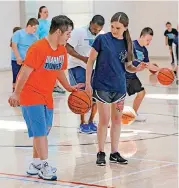  ??  ?? Volunteer Brooke Blackwood helps George Cerbu during basketball camp.