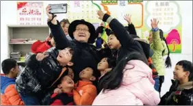  ?? CAO LI / XINHUA ?? Chick takes a selfie with children at Dawan Primary School in Jinzhai.