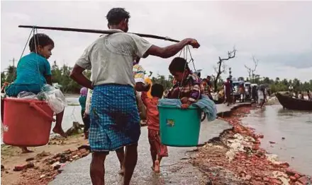  ?? AFP PIC ?? A Rohingya refugee carrying two children in buckets as they arrive in Shah Porir Dwip, Teknaf, Bangladesh, yesterday.