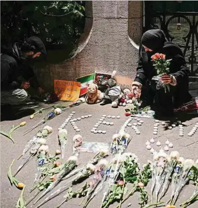  ?? Foto: AFP ?? Blumen und Kerzen vor der iranischen Botschaft in Paris erinnern an die 83 Opfer, die bei einem Anschlag des IS in Kerman getötet wurden.