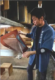  ??  ?? Yuichi Hirose, a craftsman who dyes white fabrics with meticulous­ly hand-cut stencils for a kimono, working at a century-old workshop in Tokyo.