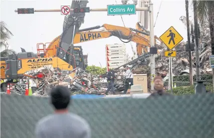  ?? REUTERS ?? A man watches from behind a street barrier at the remaining part of the Champlain Towers South complex as search-andrescue efforts resume the day after the managed demolition in Surfside, Florida, US on Monday.