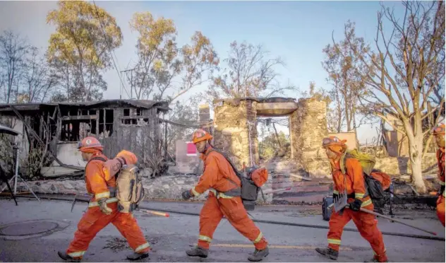  ?? Agence France-presse ?? ↑
Inmate firefighte­rs walk past a burnt home on Tigertail road in California on Monday.