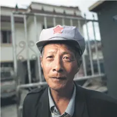  ??  ?? This picture shows Yang Renyi, who is seeking compensati­on money for his old house, posing for a portrait in front of his new house in a new village near Lianghekou, after being relocated due to the constructi­on of the Lianghekou dam.