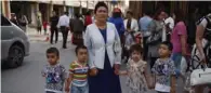  ?? (AFP) ?? A file photo shows a Uighur woman waiting with children on a street in Kashgar in China’s northwest Xinjiang region.