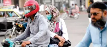  ?? Agence France-presse ?? ↑ Commuters wear face masks on a street in Karachi on Wednesday as the new coronaviru­s spreads worldwide.