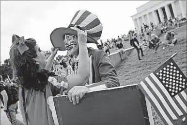  ?? [PABLO MARTINEZ MONSIVAIS/THE ASSOCIATED PRESS] ?? Theresa Lindsey, left, dressed as Snow White, helps Timothy Schlarmann, dressed as Uncle Sam, as they join other juggalos on the Washington Mall on Saturday amid three separate demonstrat­ions. While others rallied for Trump and others protested Russian...