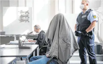  ?? FOTO: MARIJAN MURAT/DPA ?? Der Angeklagte sitzt im Schwurgeri­chtssaal des Landgerich­ts Ellwangen mit einer Jacke über dem Kopf an seinem Platz. Der 27-Jährige hat Ende Januar seine Eltern, zwei Halbgeschw­ister sowie Onkel und Tante getötet.