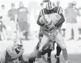  ?? JIM RASSOL/STAFF FILE PHOTO ?? It’s tough to say for sure if the offensive line will do a better job of protecting Dolphins QB Ryan Tannehill (17) in 2015.