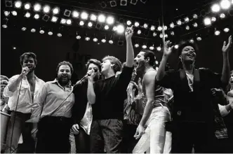  ??  ?? In this July 13, 1985, file photo, from left, George Michael of Wham!, concert promoter Harvey Goldsmith, Bono of U2, Paul McCartney, concert organizer Bob Geldof and Freddie Mercury of Queen join in the finale of the Live Aid famine relief concert, at Wembley Stadium, London.