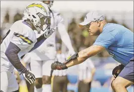  ?? Myung J. Chun Los Angeles Times ?? CHARGERS offensive coach Phil McGeoghan wears combat training gloves while working with wide receivers during training camp in Costa Mesa.