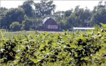  ?? NATI HARNIK — THE ASSOCIATED PRESS FILE ?? A barn with a banner reading “Trump” is seen behind a field of soy beans in Ashland, Neb. The U.S. and China have imposed import taxes on $50 billion worth of each other’s products. Ditching decades of U.S. trade policy that he says swindled America and robbed its workers, President Donald Trump insists he can save U.S. jobs and factories by abandoning or rewriting trade deals, slapping taxes on imports and waging a brutal tariff war with China, America’s biggest trading partner.