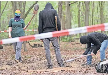  ?? FOTO: AP ?? Vermummte Klimaaktiv­isten heben im Hambacher Forst ein Loch im Boden aus. Die Besetzer rüsten sich für die geplante Rodung des Waldes im Oktober.