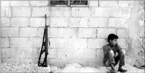  ?? — Photo by The Associated Press ?? A Syrian child sits in a village near Kafr Nabuda in the Idlib province countrysid­e, Syria.