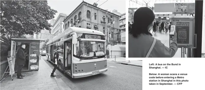  ?? ?? Left: A bus on the Bund in Shanghai. — IC
Below: A woman scans a venue code before entering a Metro station in Shanghai in this photo taken in September. — CFP