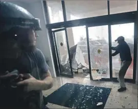  ?? Gerald Herbert Associated Press ?? A HOTEL worker in Panama City Beach, Fla., holds a door closed as it is shattered by f lying debris. Search-and-rescue missions were launched across the area.