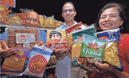  ?? MILWAUKEE JOURNAL SENTINEL ANGELA PETERSON, ?? The Sanghavi family from left, Dinesh, his son Neil and wife Bharti, display snacks to consider while watching the Olympics. They’re shown at their store, Indian Groceries & Spices at 10701 W. North Ave. in Wauwatosa, on July 9.
