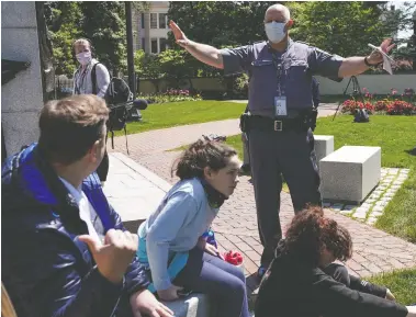  ?? KEVIN LAMARQUE / REUTERS ?? A police officer asks protesters to spread out as they gather in opposition to Virginia’s stay-at-home and business-closure orders over the global coronaviru­s outbreak, in Richmond, Va., on Thursday.