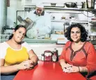  ??  ?? Nicole (left) and Nixaliz Peralta take a table at the “Maisel” exhibit’s Stage Deli, where a deli man on film slices meat in the background.