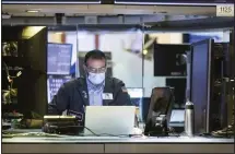  ??  ?? In this photo provided by the New York Stock Exchange, trader Aman Patel wears a protective face mask as he works on the partially reopened trading
floor. (AP)