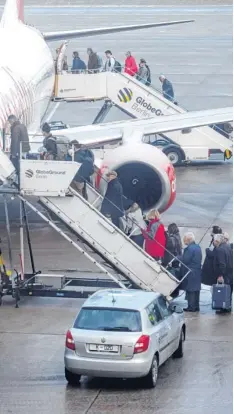  ?? Foto: dpa ?? Die einen stehen im Regen, während die anderen im Flugzeug umständlic­h ihren Koffer verstauen.