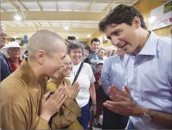  ?? CP PHOTO ?? Prime Minister Justin Trudeau is greeted by Buddhist monks as he visits the curling club in Montague, P.E.I., on Thursday.