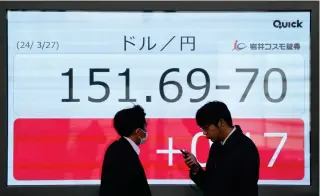  ?? PHOTO BY KAZUHIRO NOGI/AFP ?? Pedestrian­s walk in front of an electronic board showing the yen versus US dollar exchange rate along a street in Tokyo on Wednesday, March 27, 2024.