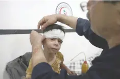  ?? — AFP ?? An injured Syrian child receives treatment at a makeshift hospital following a reported air strike on the rebel-held town of Douma, east of the capital Damascus, on Tueasday.