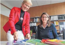  ?? FOTO: INGEBORG WAGNER ?? So sahen sie mal aus: Rektorin Christiane Sturm (links) und Angela Peinemann zeigen „alte“Klassenbüc­her.