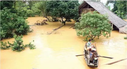  ?? — AFP ?? HANOI PROVINCE: This picture shows villagers in a boat transporti­ng boxes of instant noodles they received as relief aid past flooded homes in a village in Huong Khe district in the central province of Ha Tinh.