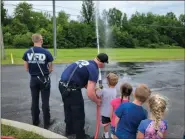  ?? ?? Vermilion firefighte­rs show Safety Town participan­ts the fire hoses.